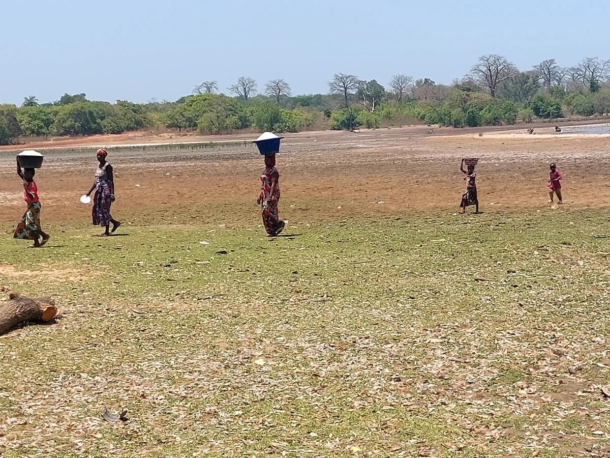 Femmes traversant une plaine inondable avec des bassines